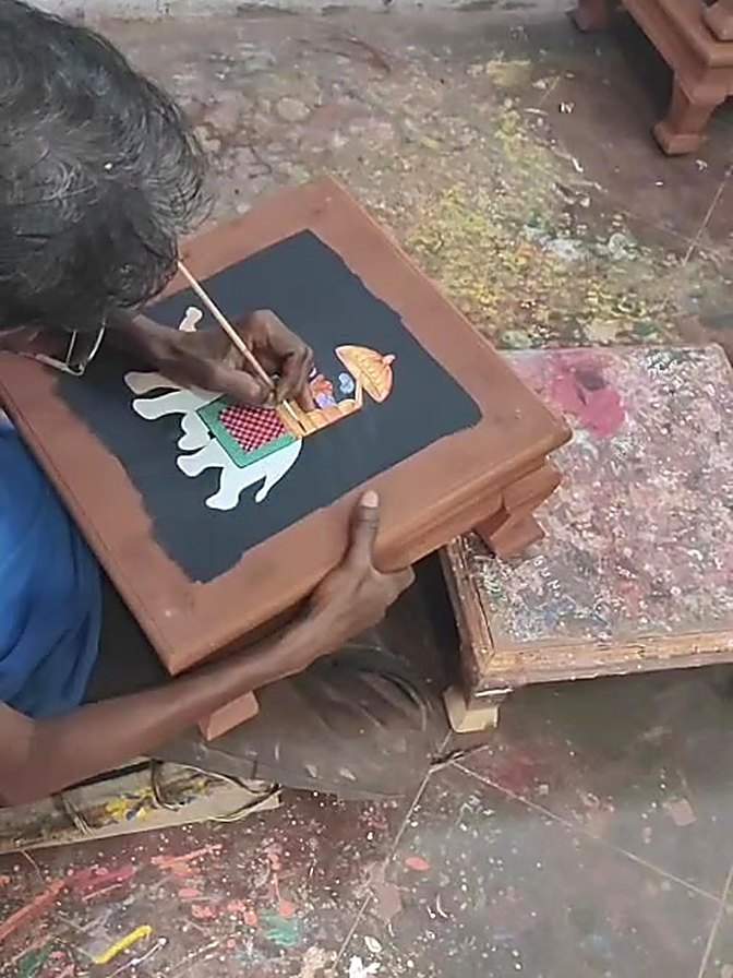 Artisan hand painting a fine motif with a brush