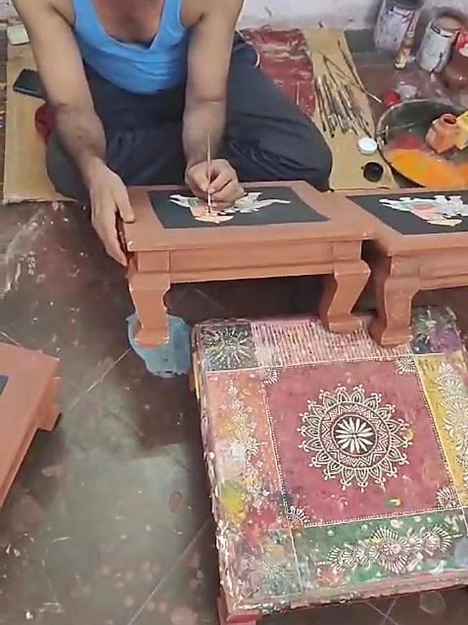 A Premloom artisan hand painting a wooden chowki in the workshop in Rajasthan